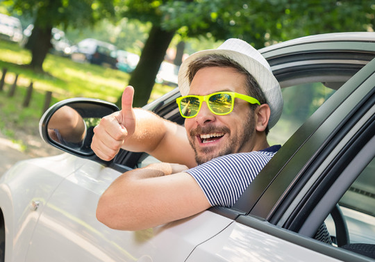 Un homme aux lunettes jaunes à la fenêtre de sa voiture