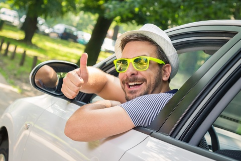 Un homme aux lunettes jaunes à la fenêtre de sa voiture